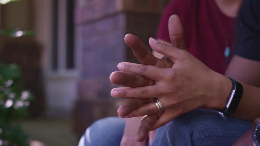 A couple hold hands while sitting outside