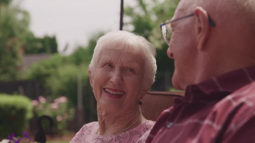 A couple sit in their yard together smiling