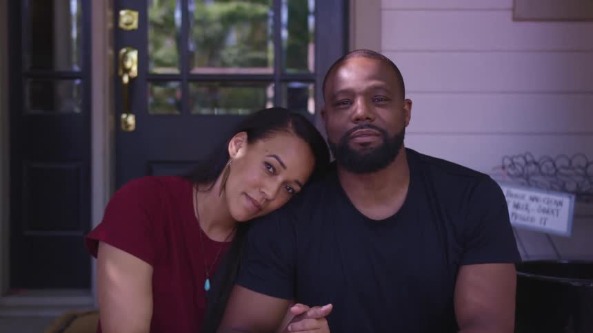 Husband and wife are sitting together outside of their house