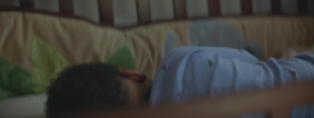 A mother watches as her baby crawls in his crib