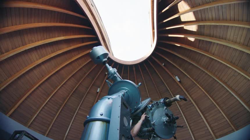 A telescope rotates within an observatory during the day