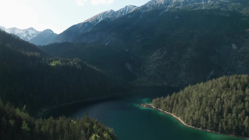 A river surrounded by trees with a mountain range the sky and clouds in the background