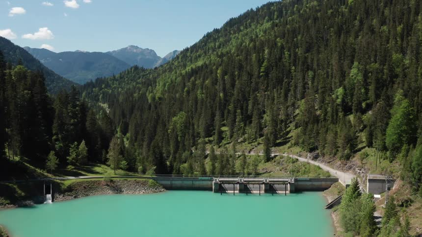 Lake with mountain forests on each side with a bridge across the lake and a road