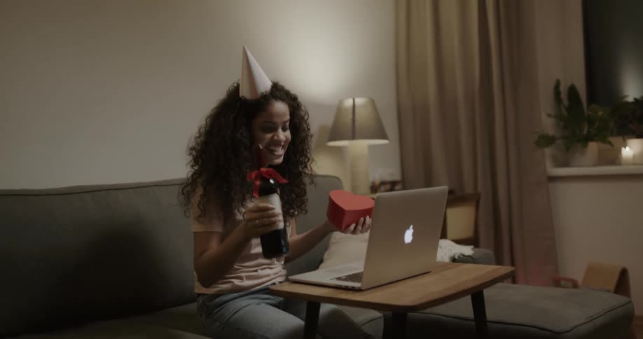 Woman wearing a party hat celebrating virtual birthday on a laptop