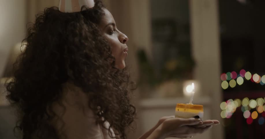 Young girl blowing a birthday cake on a video call through a laptop at home