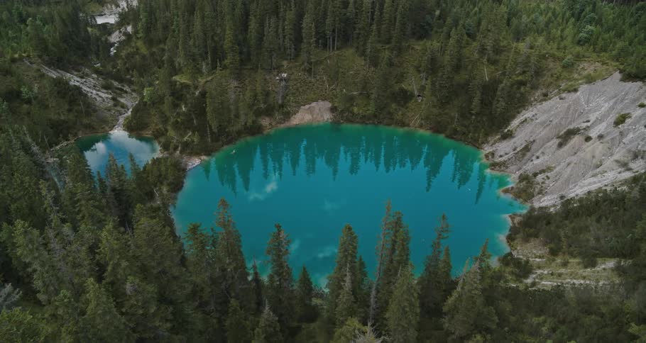 Caldera lake with surrounding forest and trees reflecting in the water