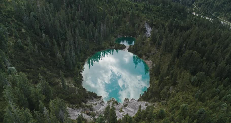 Caldera lake with surrounding forest and clouds reflecting in the water