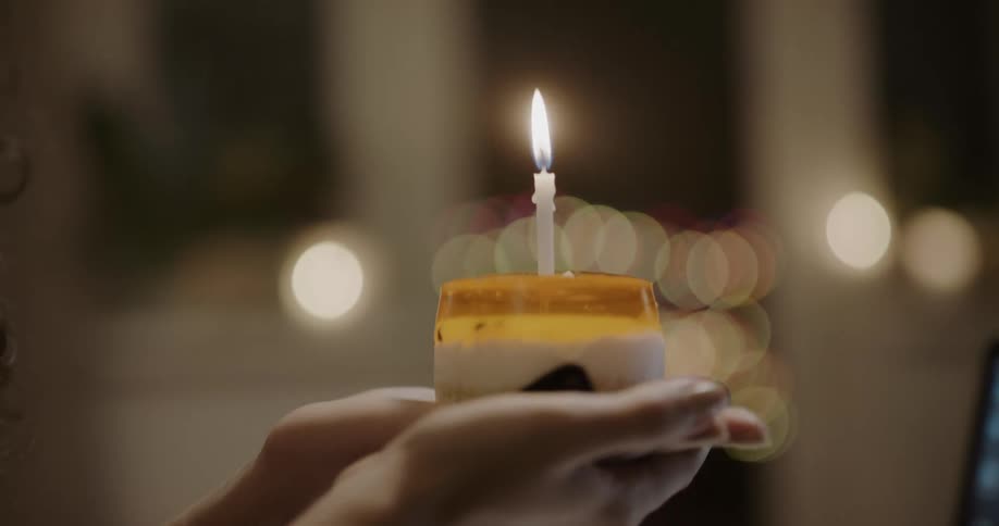 A woman blowing out a candle on dessert then smiling and blowing kisses