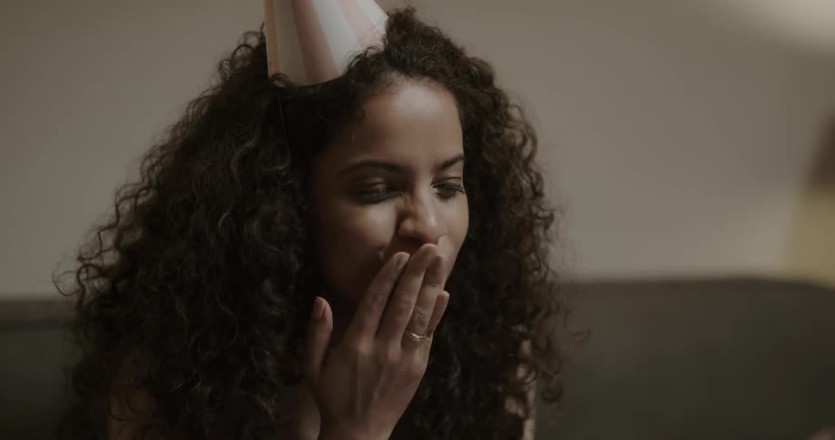 Woman celebrating a virtual birthday blowing out candle and waving to family