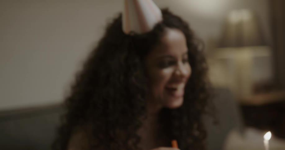 A woman smiling and laughing while celebrating a birthday over video chat