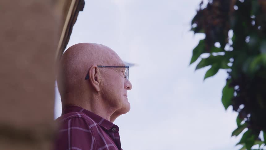 A a man standing on a patio staring off into the distance