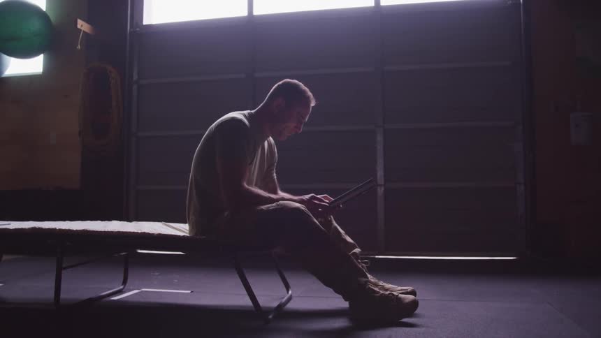 A man in a room with a military uniform sitting and looking at a picture in a frame
