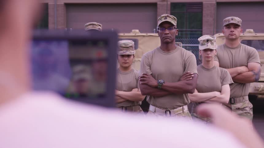 A photographer directing a mixed troop of american soldiers for a photo