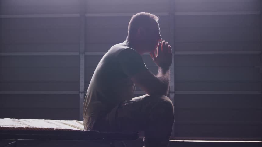 A man deep in thought while sitting on an indoor bench