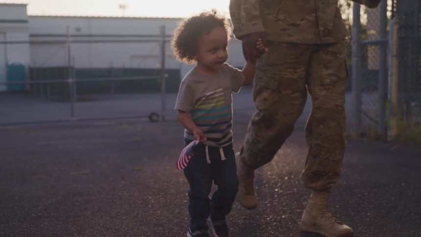 A soldier walks while holding his young sons hand