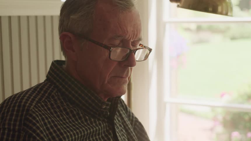 An elderly man sitting around reading something