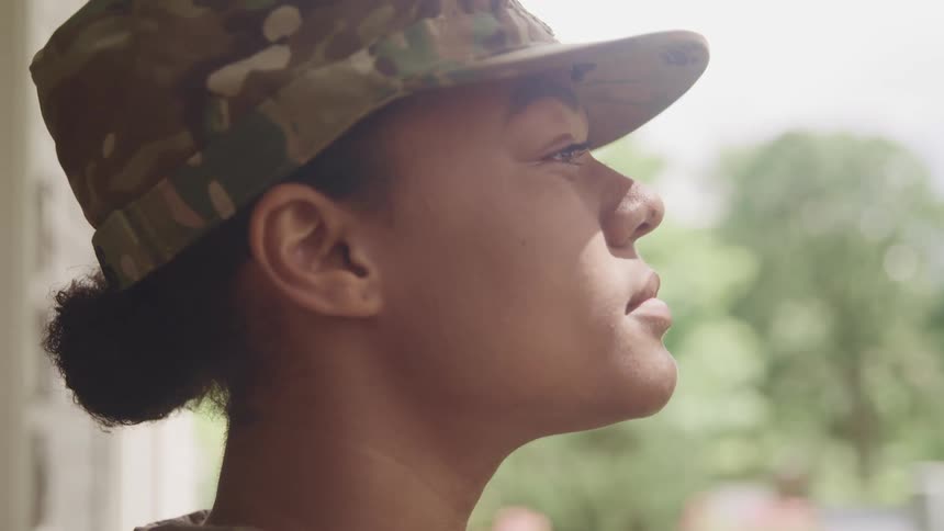 A military woman is wearing a hat and standing outdoors in spring