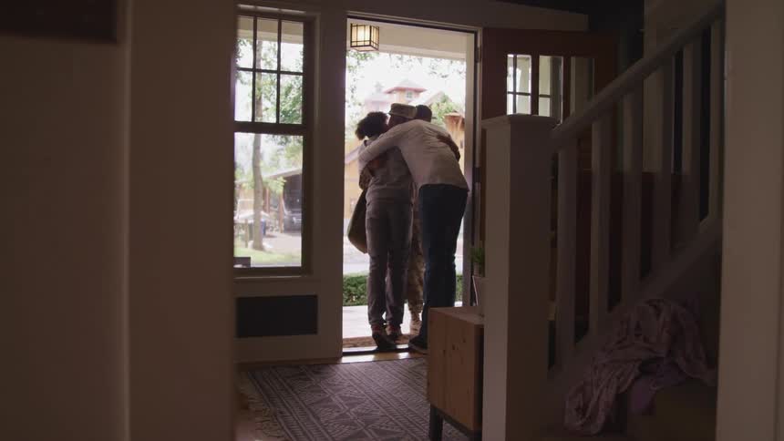 Three people are hugging in the doorway