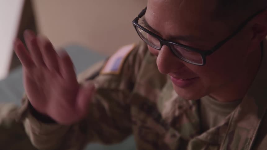 A soldier in uniform waves at someone out of frame