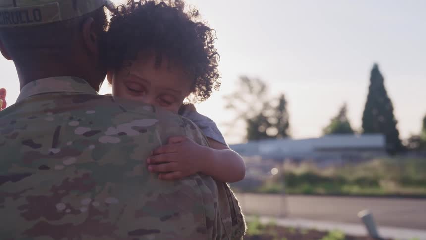 African american soldier holding toddler son in his arms outdoors