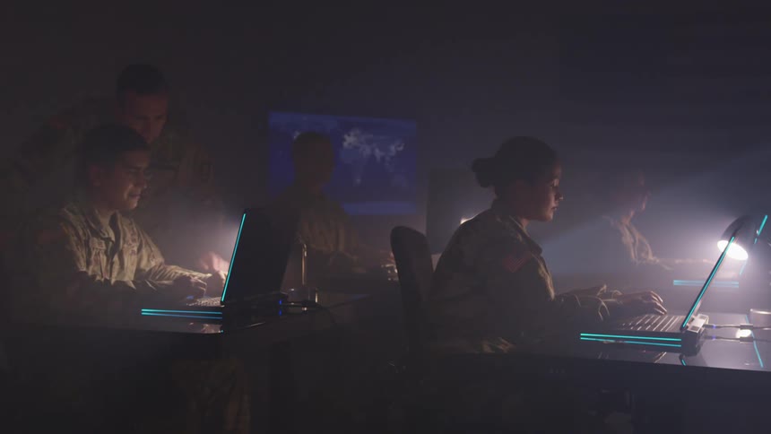A group of military people that are typing on laptops