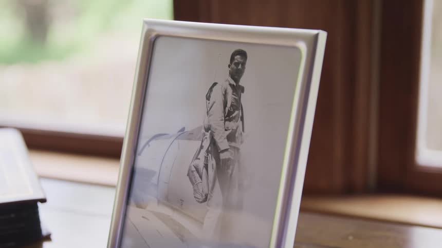 A framed black and white photograph of a man sitting on a table