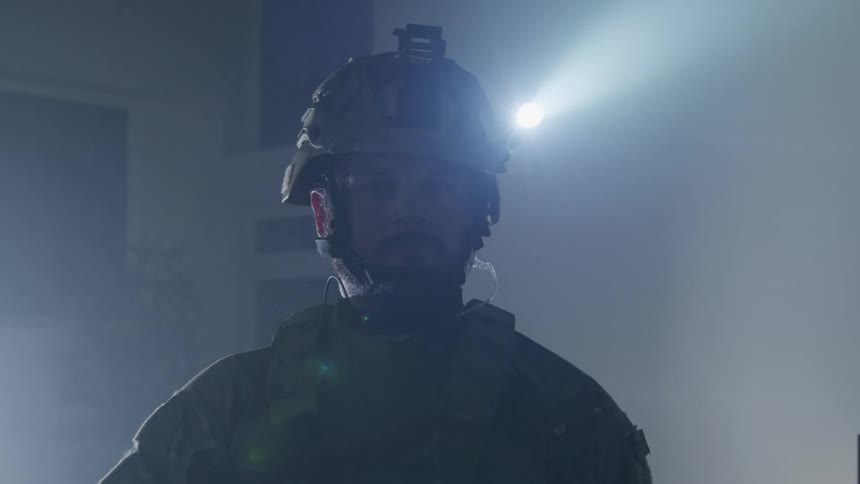 A firefighter standing in a smoky building with a headlamp