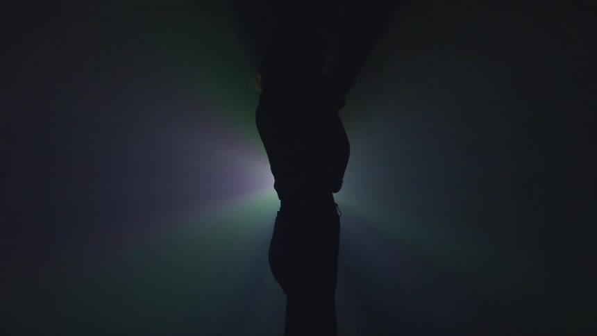 A dancer twirls in a circle under a flashing light