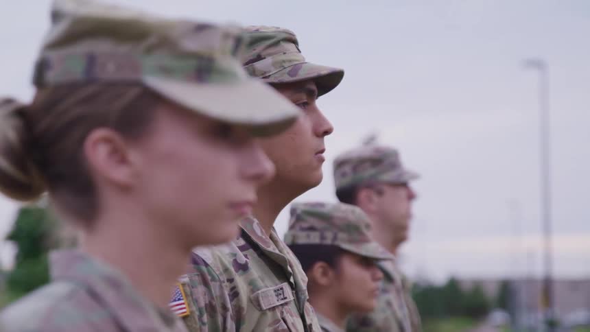 A group of soldiers standing outside staring off into the distance