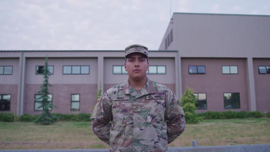 A man in a military uniform with trees a building the sky and clouds in the background