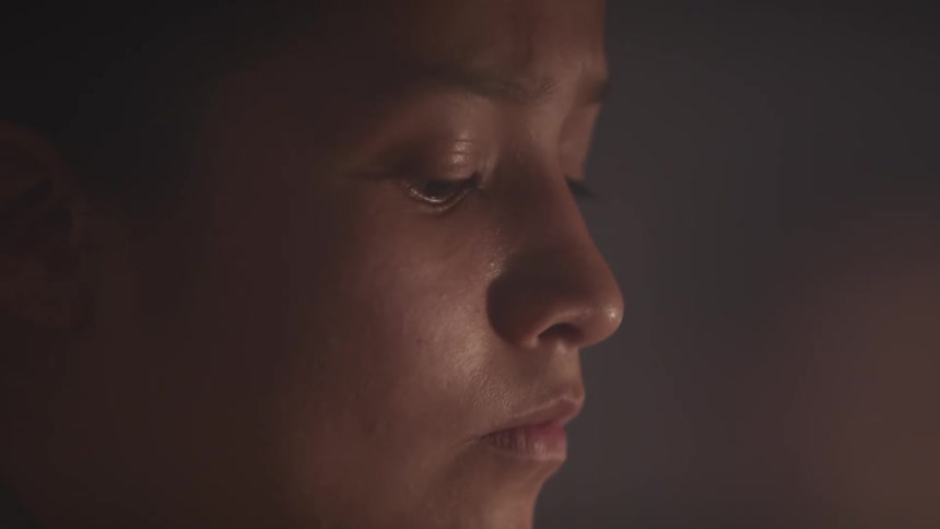 A young woman indoors looks up at something in front of her