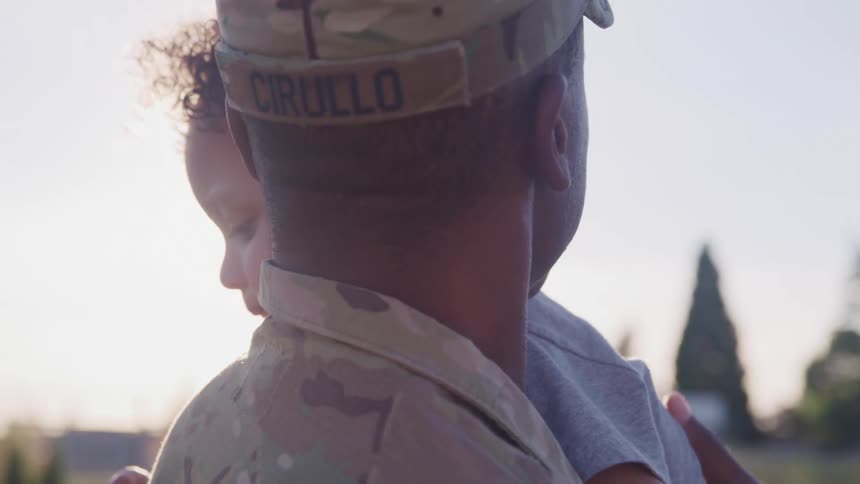 A soldier holds his young son and rubs his back