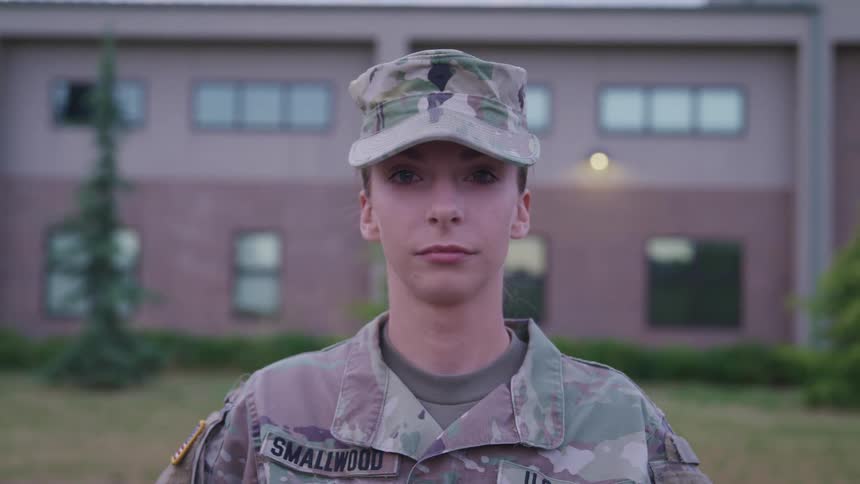 A female soldier is standing outside the building