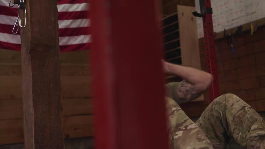 Strong muscular american soldier doing push ups on the floor of a gym under a flag