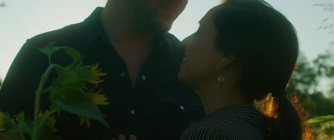 A husband and wife staring at each other hugging outdoors