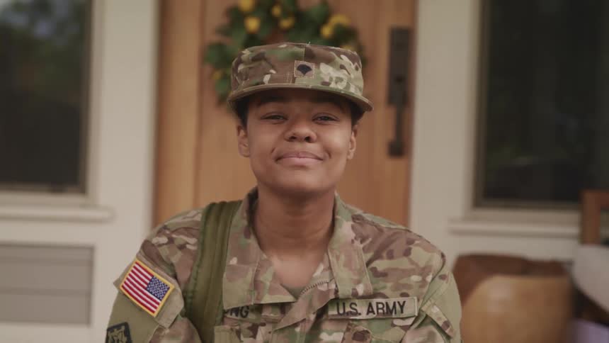 A female american soldier at home looking up at the camera