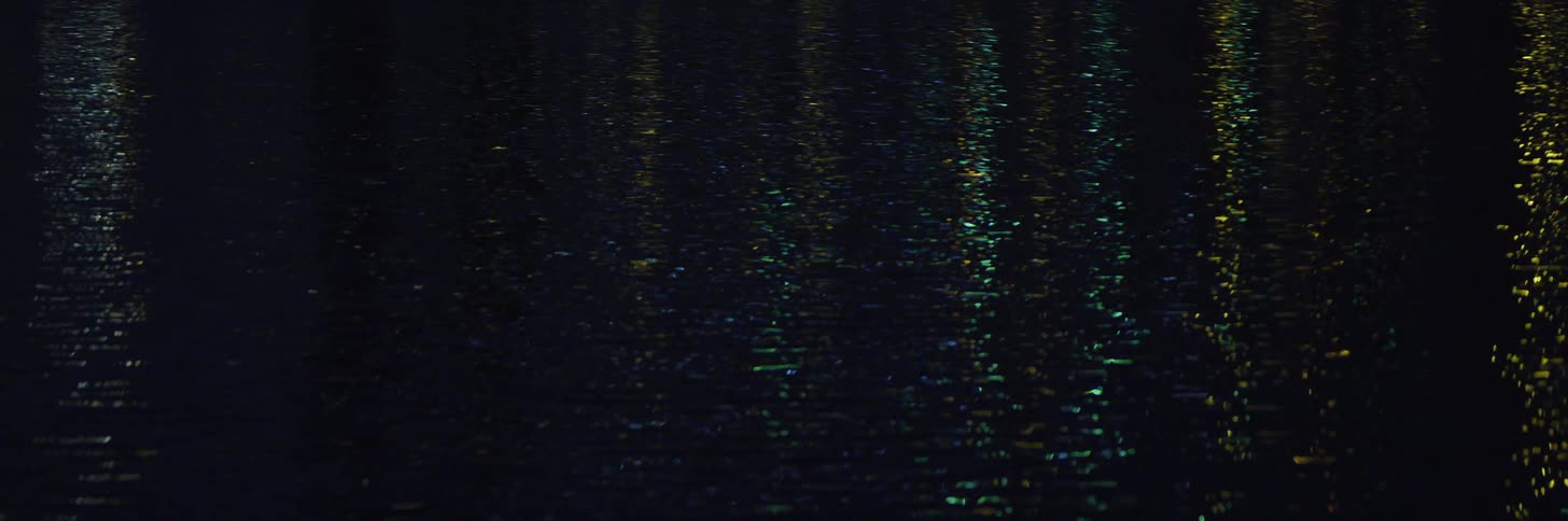 Colorful city night lights reflect on the surface of a river at night