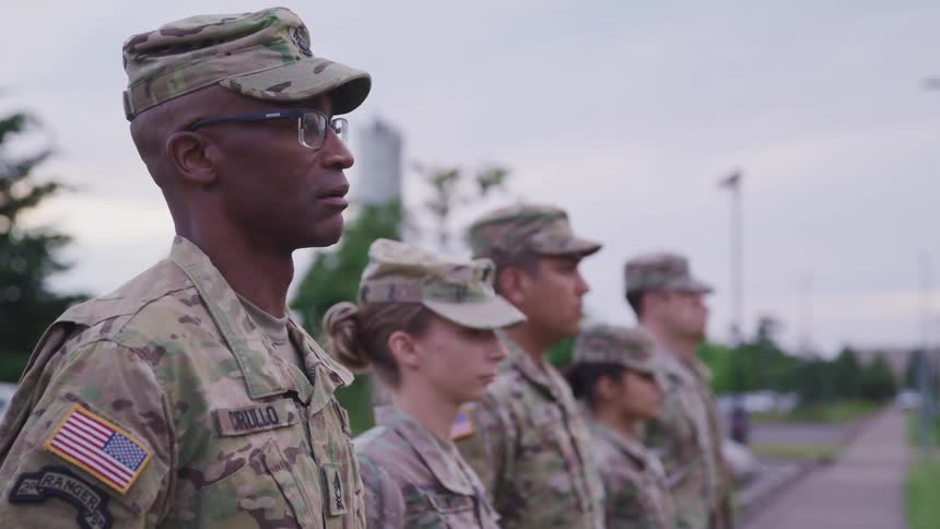 A small group of soldiers standing on a walkway salute at the same time