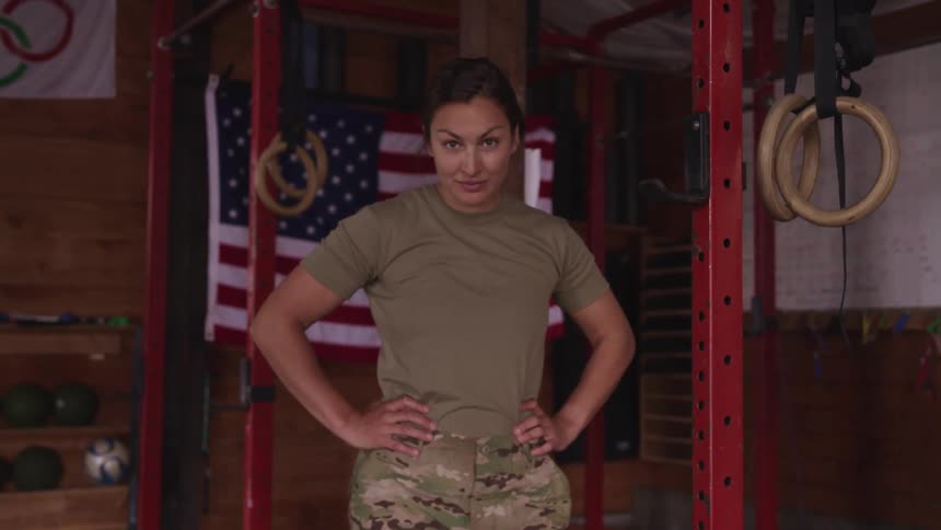 A woman in military clothing looking forward in front of workout machines