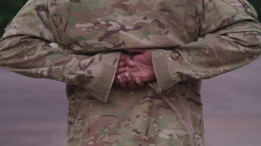 A soldier stands at ease outside