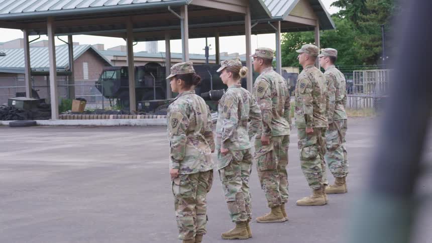 Military people stand at attention and salute in lot at base
