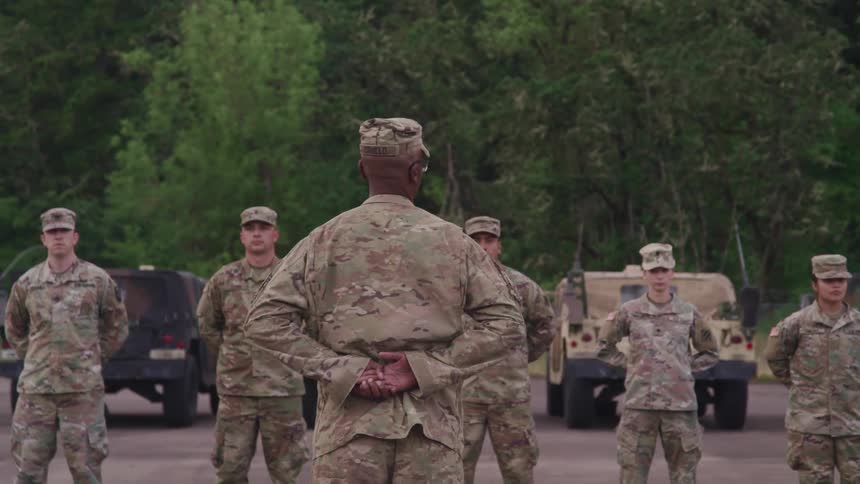Soldiers stand at attention near woods