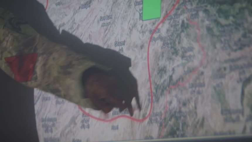 A soldier is presenting a map on the projector screen