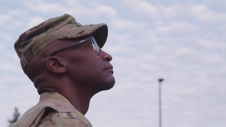 A soldier is looking up at the cloudy sky