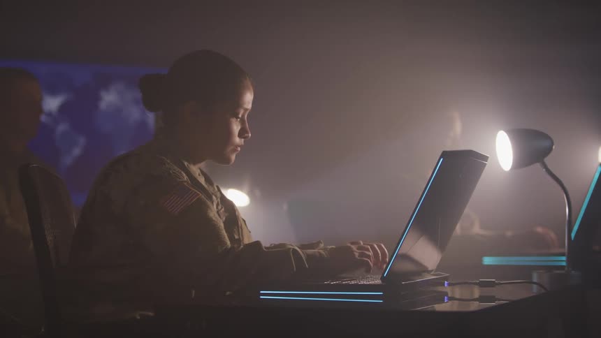 Female american soldier working on a laptop in a dimly lit room filled with smoke