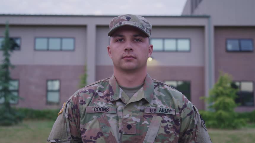 Amercian soldier standing in front of a building looking at the camera