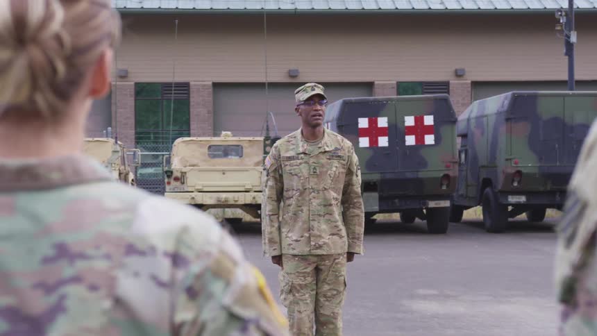 Military soldiers are standing outdoors and saluting
