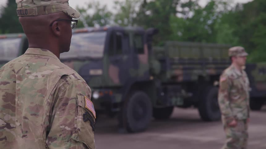 United states army drill instructor training a soldier in the yard next to trucks