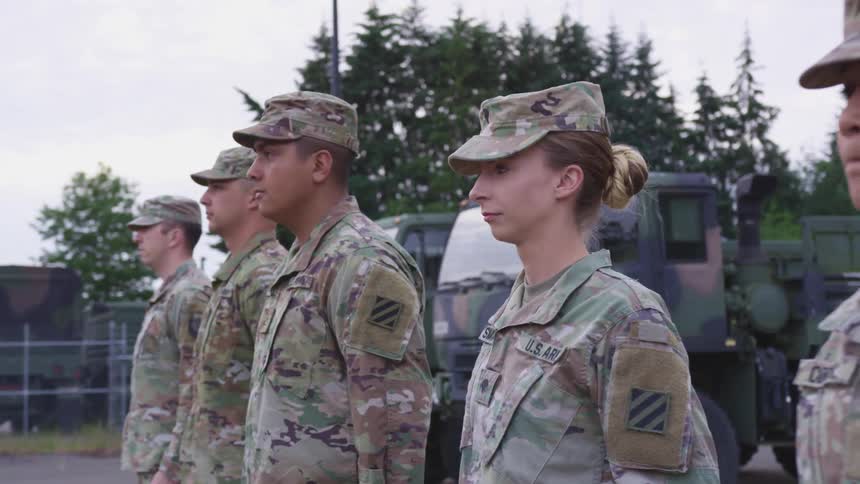 Soldiers lined up outside in camouflage uniforms