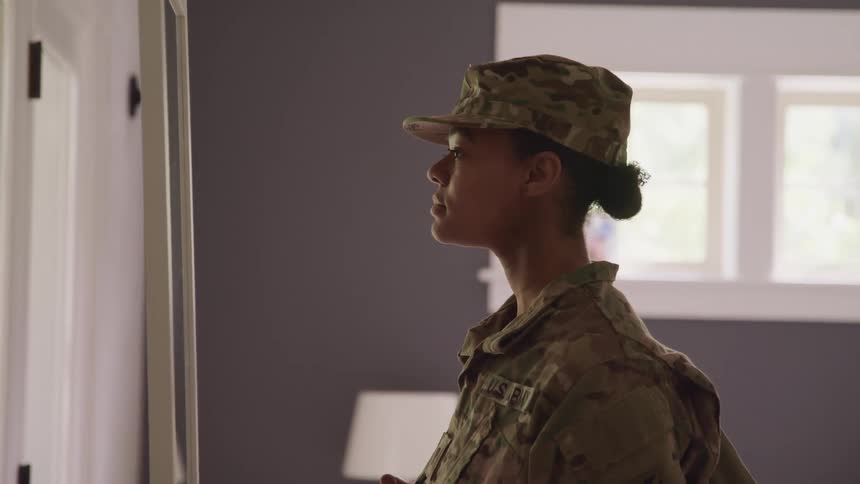 Woman wearing fatigues stands near doorway